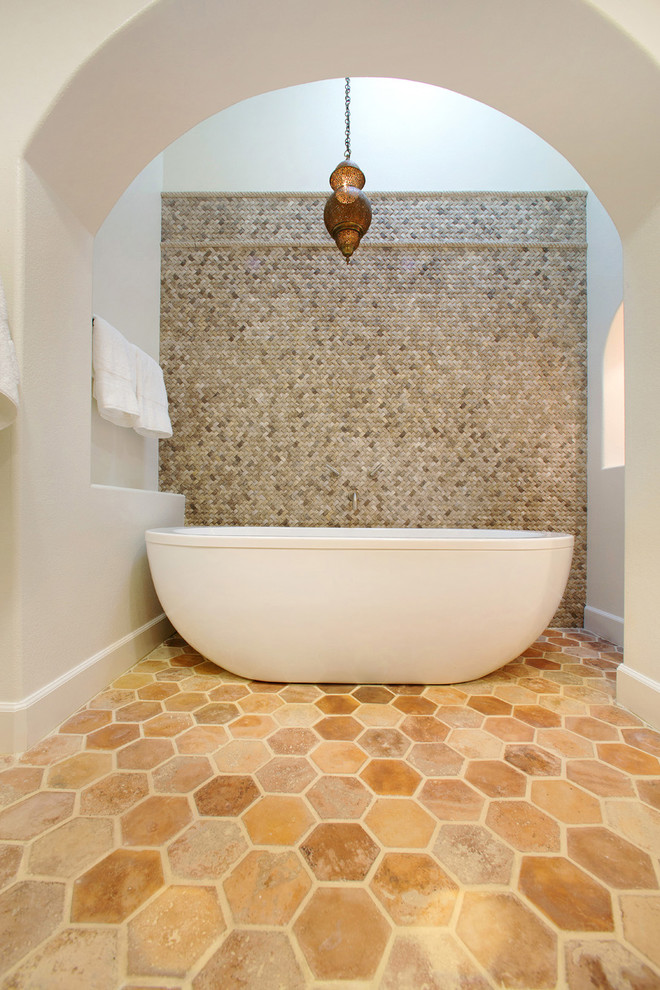 This is an example of a large mediterranean bathroom in Los Angeles with open cabinets, white cabinets, a claw-foot bath, a double shower, beige tiles, stone tiles, white walls, cement flooring, a console sink, brown floors and a hinged door.