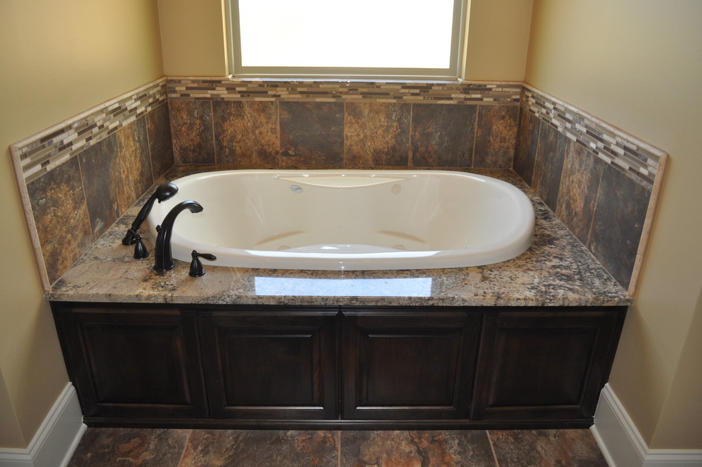 Foto på ett mellanstort vintage en-suite badrum, med luckor med upphöjd panel, skåp i mörkt trä, granitbänkskiva, ett platsbyggt badkar, flerfärgad kakel, porslinskakel, bruna väggar och klinkergolv i porslin