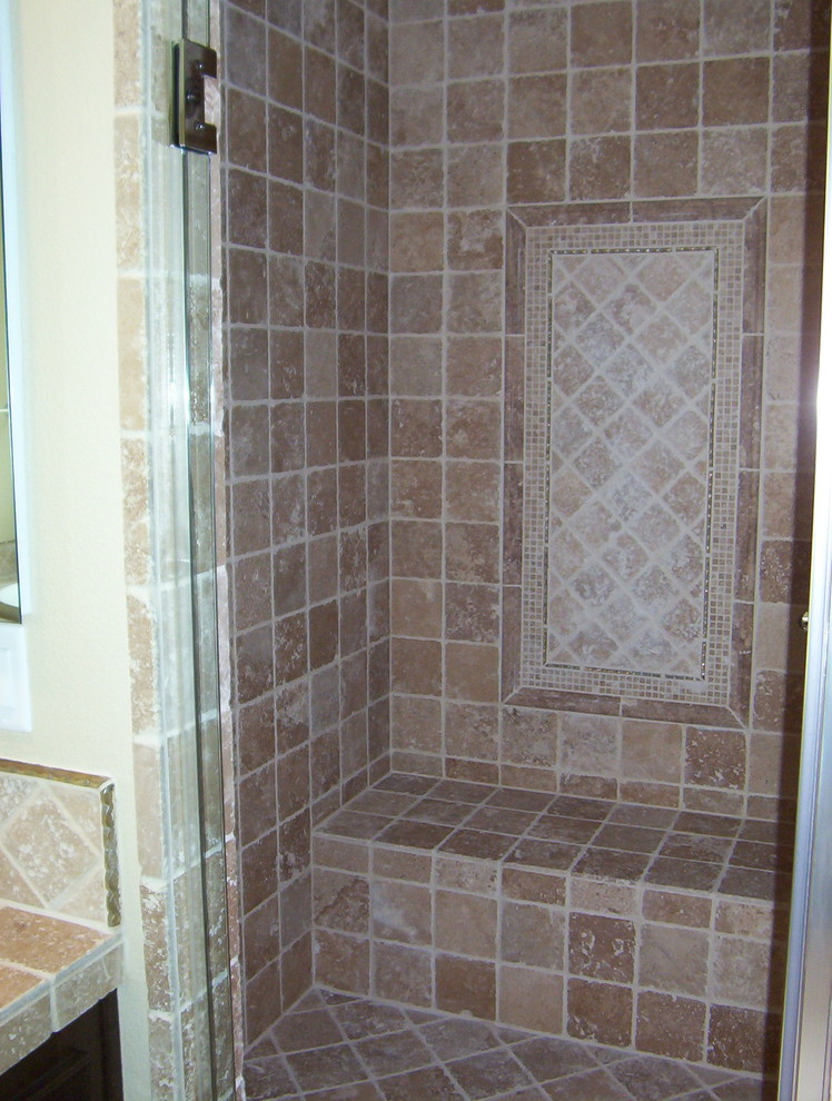 Immagine di una stanza da bagno mediterranea con ante in legno bruno, top piastrellato, doccia ad angolo, piastrelle beige e piastrelle in pietra