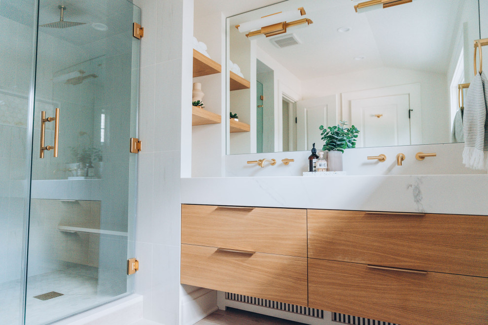 Пример оригинального дизайна: главная ванная комната среднего размера в стиле модернизм с плоскими фасадами, светлыми деревянными фасадами, душем в нише, белой плиткой, полом из керамической плитки, накладной раковиной, мраморной столешницей, бежевым полом, душем с распашными дверями, белой столешницей, сиденьем для душа, тумбой под две раковины, подвесной тумбой и кессонным потолком