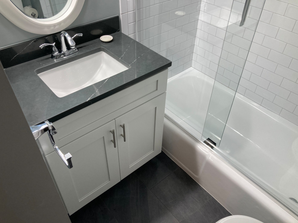Design ideas for a small modern family bathroom in DC Metro with shaker cabinets, white cabinets, an alcove bath, an alcove shower, a two-piece toilet, white tiles, porcelain tiles, grey walls, porcelain flooring, a submerged sink, quartz worktops, grey floors, a sliding door, grey worktops, a wall niche, a single sink and a built in vanity unit.