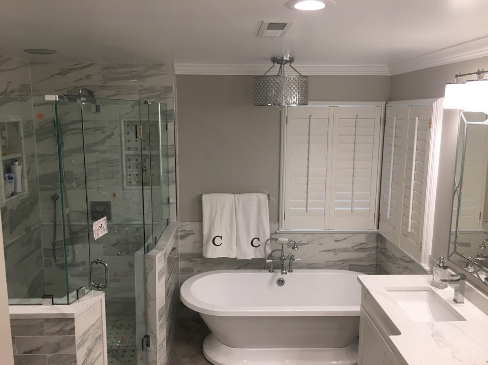 Exempel på ett mellanstort klassiskt vit vitt en-suite badrum, med luckor med infälld panel, vita skåp, ett fristående badkar, en hörndusch, grå kakel, marmorkakel, grå väggar, marmorgolv, granitbänkskiva, grått golv, dusch med gångjärnsdörr och ett undermonterad handfat