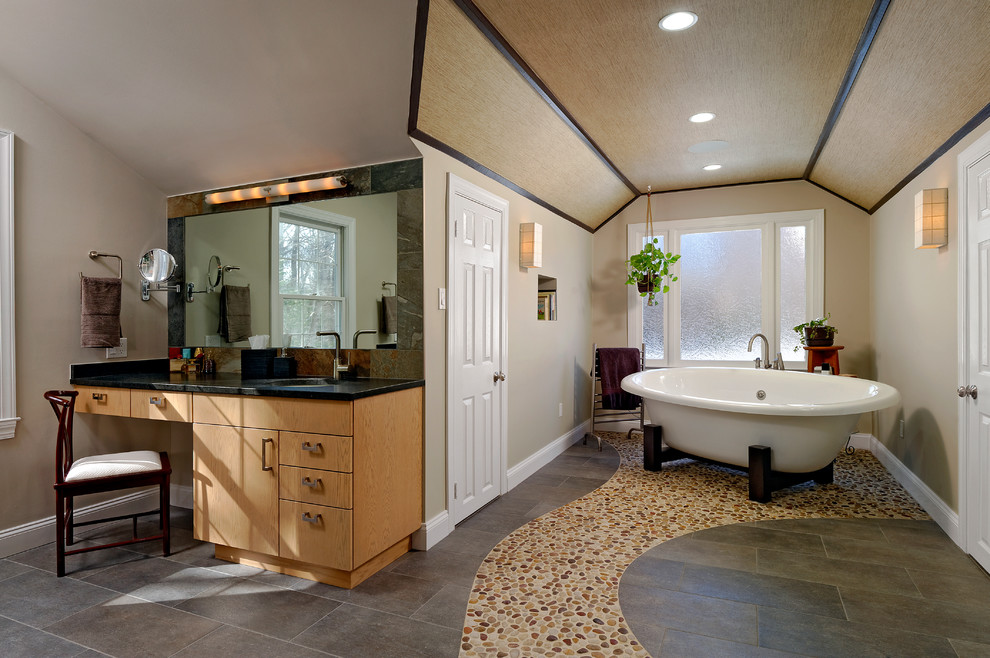 Imagen de cuarto de baño tradicional renovado con armarios con paneles lisos, puertas de armario de madera clara y bañera exenta