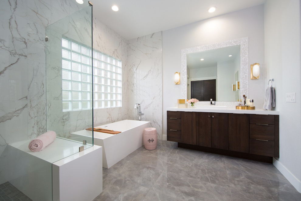 Свежая идея для дизайна: ванная комната среднего размера в современном стиле с плоскими фасадами, темными деревянными фасадами, отдельно стоящей ванной, угловым душем, белой плиткой, белыми стенами, душевой кабиной, накладной раковиной, серым полом и белой столешницей - отличное фото интерьера