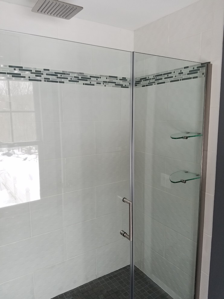 Modern inredning av ett litet en-suite badrum, med släta luckor, vita skåp, en dusch i en alkov, en toalettstol med separat cisternkåpa, vit kakel, grå väggar, grått golv och dusch med gångjärnsdörr