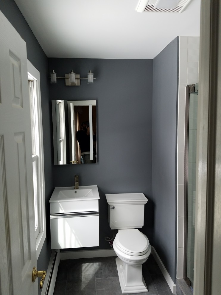 Inredning av ett modernt litet en-suite badrum, med släta luckor, vita skåp, en dusch i en alkov, en toalettstol med separat cisternkåpa, vit kakel, grå väggar, grått golv och dusch med gångjärnsdörr