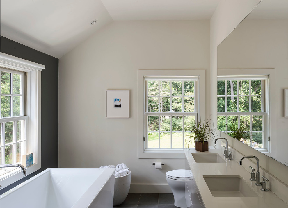 Стильный дизайн: большая главная ванная комната в современном стиле с плоскими фасадами, отдельно стоящей ванной, бежевыми стенами, полом из керамической плитки, врезной раковиной и столешницей из искусственного камня - последний тренд