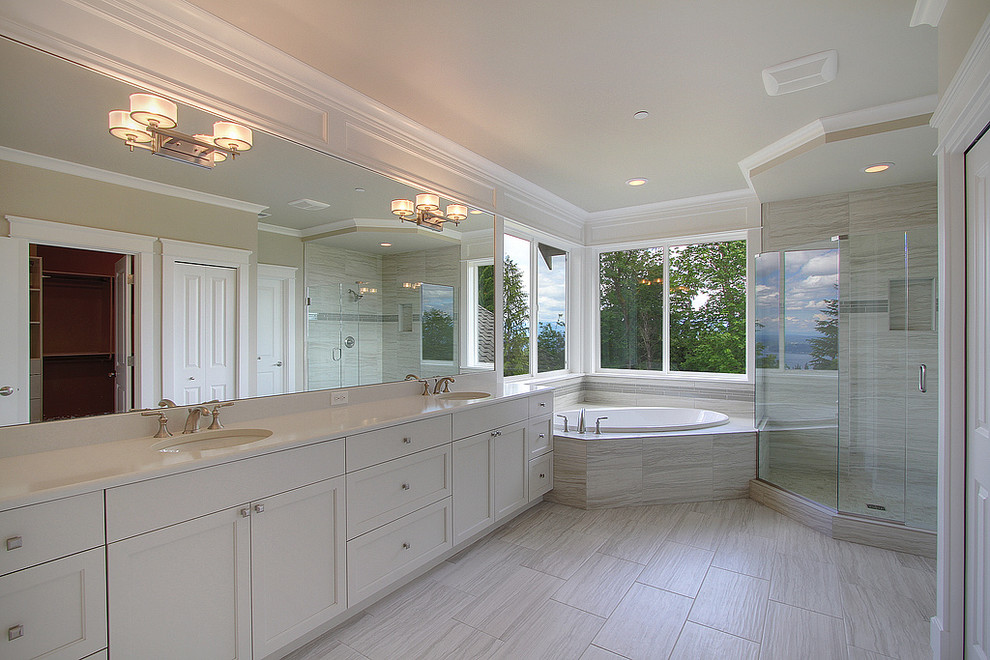 Example of a large transitional master gray tile and porcelain tile porcelain tile and gray floor bathroom design in Seattle with recessed-panel cabinets, white cabinets, beige walls, an undermount sink, solid surface countertops, a hinged shower door and white countertops