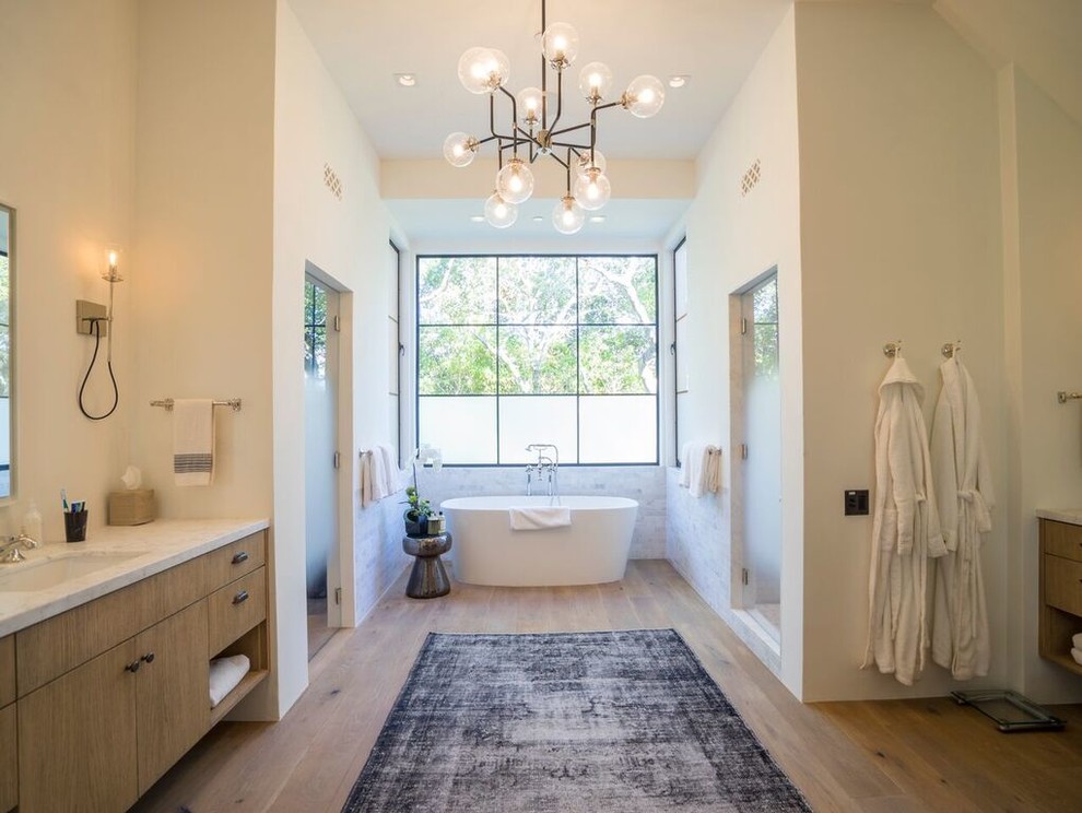 This is an example of a traditional ensuite bathroom in Santa Barbara with a freestanding bath, an alcove shower, grey tiles, white tiles, medium hardwood flooring, a submerged sink and a hinged door.