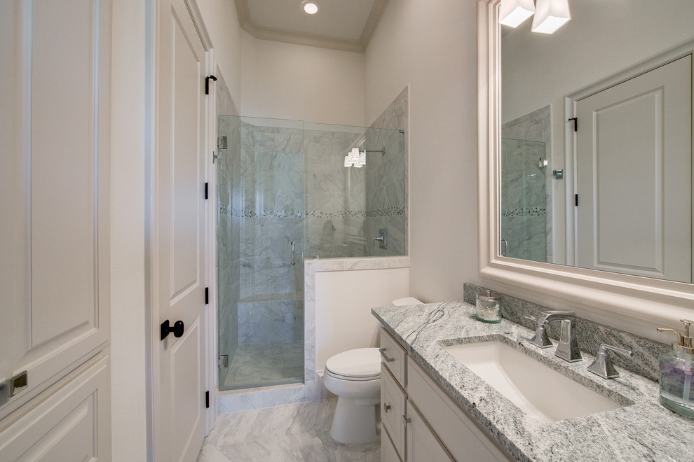 Exemple d'une salle de bain chic de taille moyenne avec un placard à porte affleurante, des portes de placard blanches, un carrelage gris, du carrelage en marbre, un mur gris, un sol en marbre, un lavabo encastré, un plan de toilette en quartz modifié, un sol gris et une cabine de douche à porte battante.