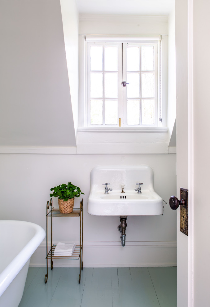 Modelo de cuarto de baño único clásico con bañera con patas, paredes blancas, suelo de madera pintada, lavabo suspendido y suelo turquesa