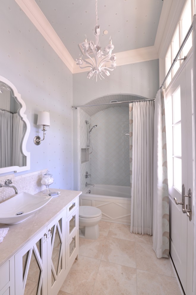 Photo of a small traditional bathroom in Dallas with a vessel sink, white cabinets, a built-in bath, a shower/bath combination, blue walls, glass-front cabinets, solid surface worktops, blue tiles, glass tiles and porcelain flooring.