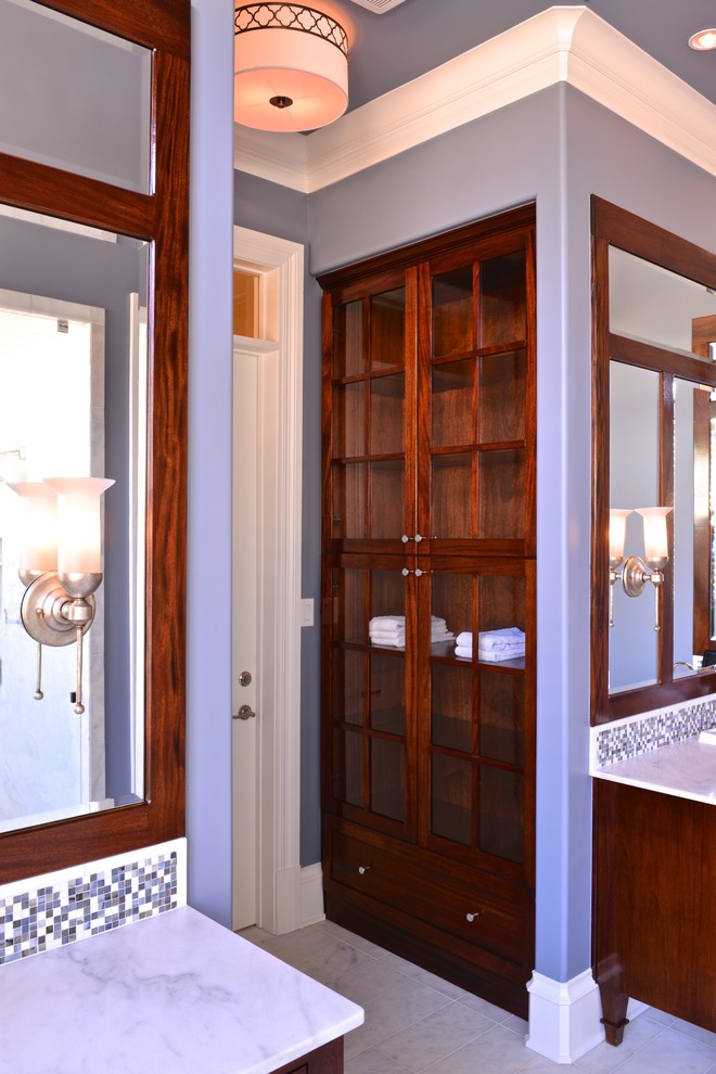 Diseño de cuarto de baño clásico renovado grande con armarios con paneles lisos, puertas de armario de madera en tonos medios, encimera de mármol, bañera exenta, sanitario de una pieza, baldosas y/o azulejos blancos, paredes grises y suelo de mármol