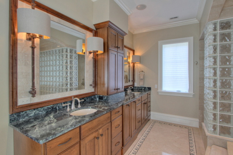 Design ideas for a large traditional ensuite bathroom in Atlanta with beaded cabinets, medium wood cabinets, a built-in bath, an alcove shower, beige tiles, limestone tiles, beige walls, limestone flooring, a submerged sink and engineered stone worktops.