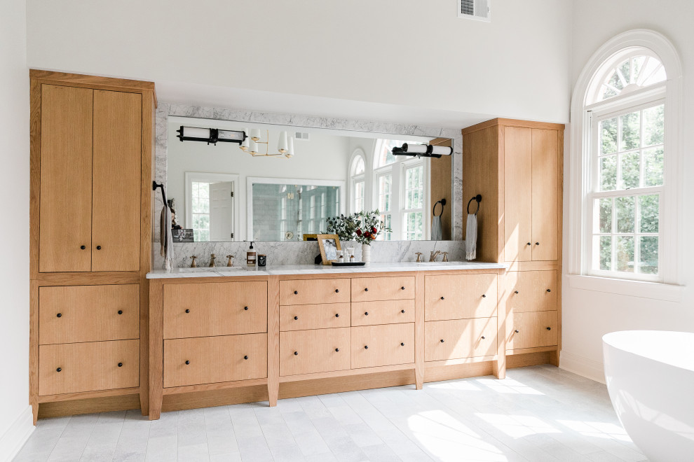 This is an example of a large classic ensuite bathroom in Other with light wood cabinets, a freestanding bath, white walls, marble flooring, a submerged sink, marble worktops, white worktops, double sinks, a built in vanity unit, flat-panel cabinets and white floors.