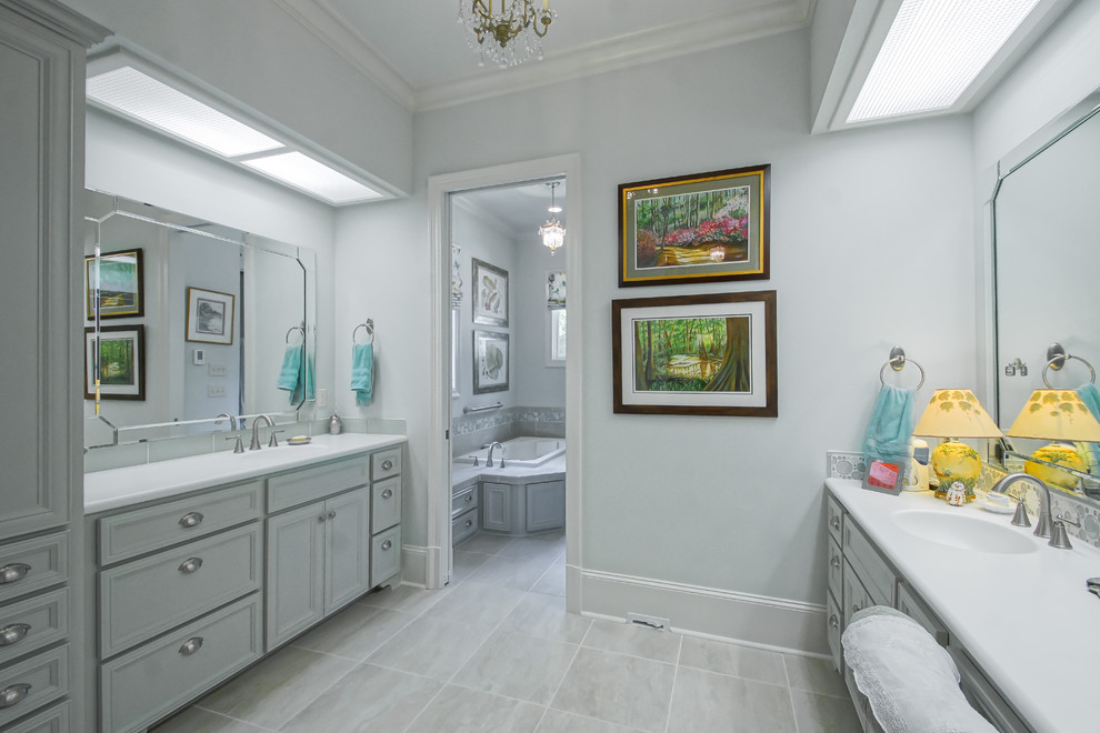 Drop-in bathtub - mid-sized traditional master gray tile and porcelain tile porcelain tile drop-in bathtub idea in New Orleans with an integrated sink, raised-panel cabinets, white cabinets, solid surface countertops, a one-piece toilet and white walls