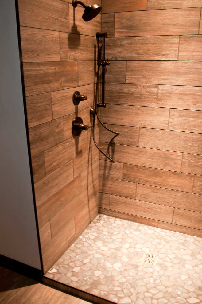 Réalisation d'une salle de bain design en bois brun de taille moyenne avec un lavabo encastré, un placard avec porte à panneau encastré, un plan de toilette en granite, WC suspendus, un carrelage beige, une plaque de galets, un mur beige et un sol en bois brun.