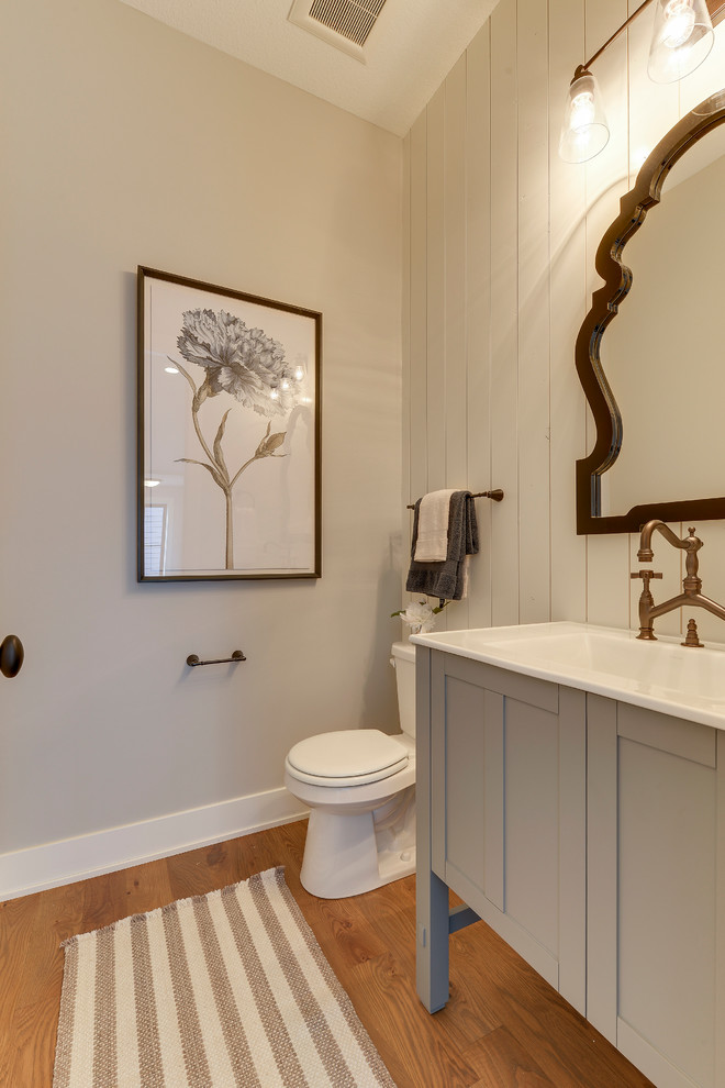 Kleines Country Duschbad mit blauen Schränken, Toilette mit Aufsatzspülkasten, grauer Wandfarbe, Mineralwerkstoff-Waschtisch, braunem Holzboden, braunem Boden, Schrankfronten im Shaker-Stil und integriertem Waschbecken in Minneapolis