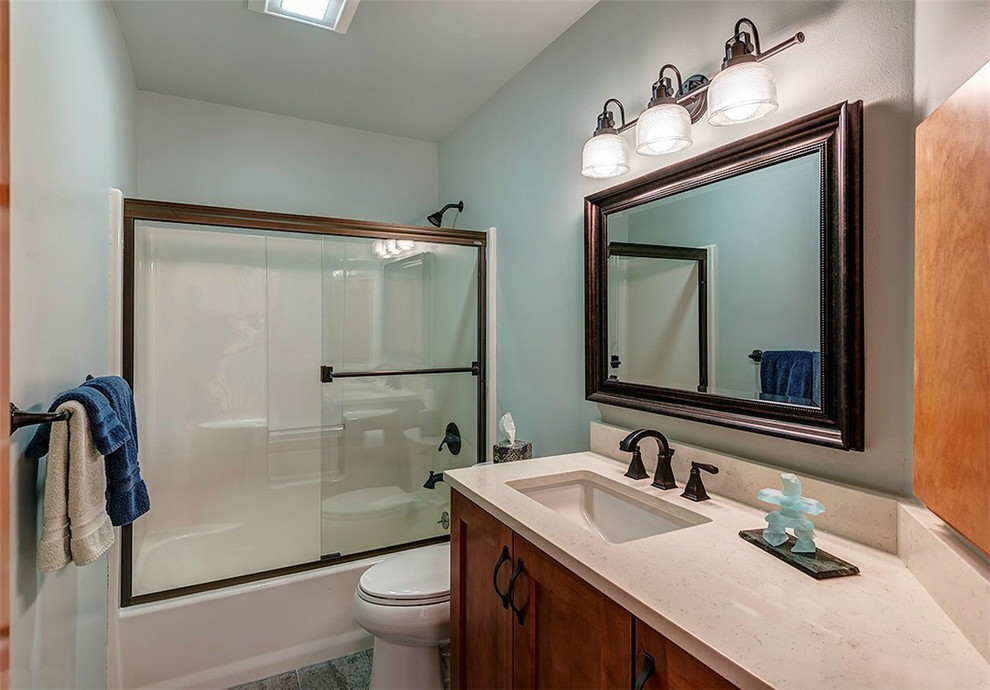Example of a mid-sized arts and crafts kids' gray tile and porcelain tile porcelain tile alcove shower design in Seattle with shaker cabinets, medium tone wood cabinets, a one-piece toilet, blue walls, an undermount sink and quartz countertops