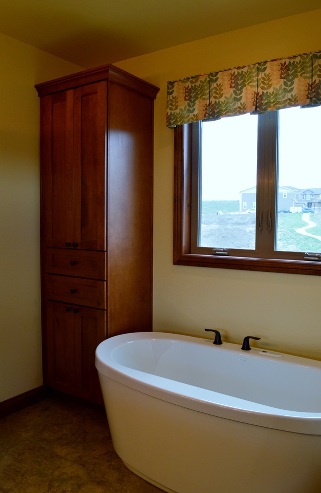 Пример оригинального дизайна: главная ванная комната среднего размера в стиле кантри с фасадами с утопленной филенкой, фасадами цвета дерева среднего тона и отдельно стоящей ванной