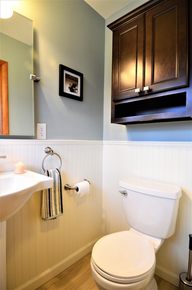 Small classic shower room bathroom in Milwaukee with raised-panel cabinets, dark wood cabinets, a two-piece toilet, grey walls, light hardwood flooring, a pedestal sink, solid surface worktops and beige floors.