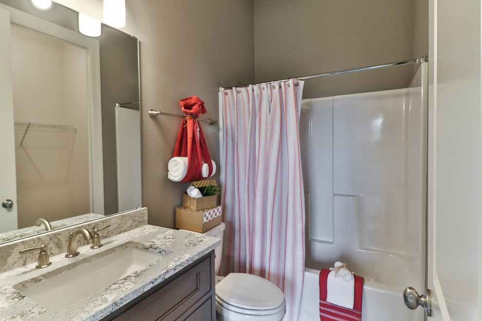 Bild på ett mellanstort vintage badrum med dusch, med skåp i shakerstil, skåp i mörkt trä, ett badkar i en alkov, en dusch/badkar-kombination, en toalettstol med separat cisternkåpa, vit kakel, porslinskakel, beige väggar, vinylgolv, ett undermonterad handfat, granitbänkskiva, grått golv och dusch med duschdraperi