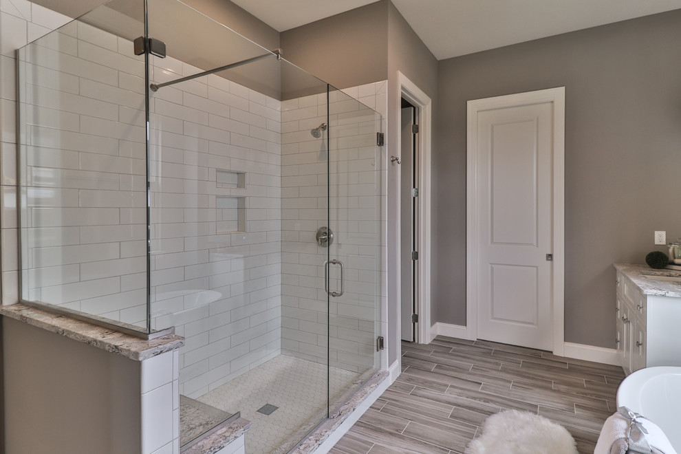 Inspiration for a medium sized traditional ensuite bathroom in St Louis with shaker cabinets, dark wood cabinets, a freestanding bath, an alcove shower, a two-piece toilet, white tiles, porcelain tiles, beige walls, vinyl flooring, a submerged sink, granite worktops, grey floors and a hinged door.