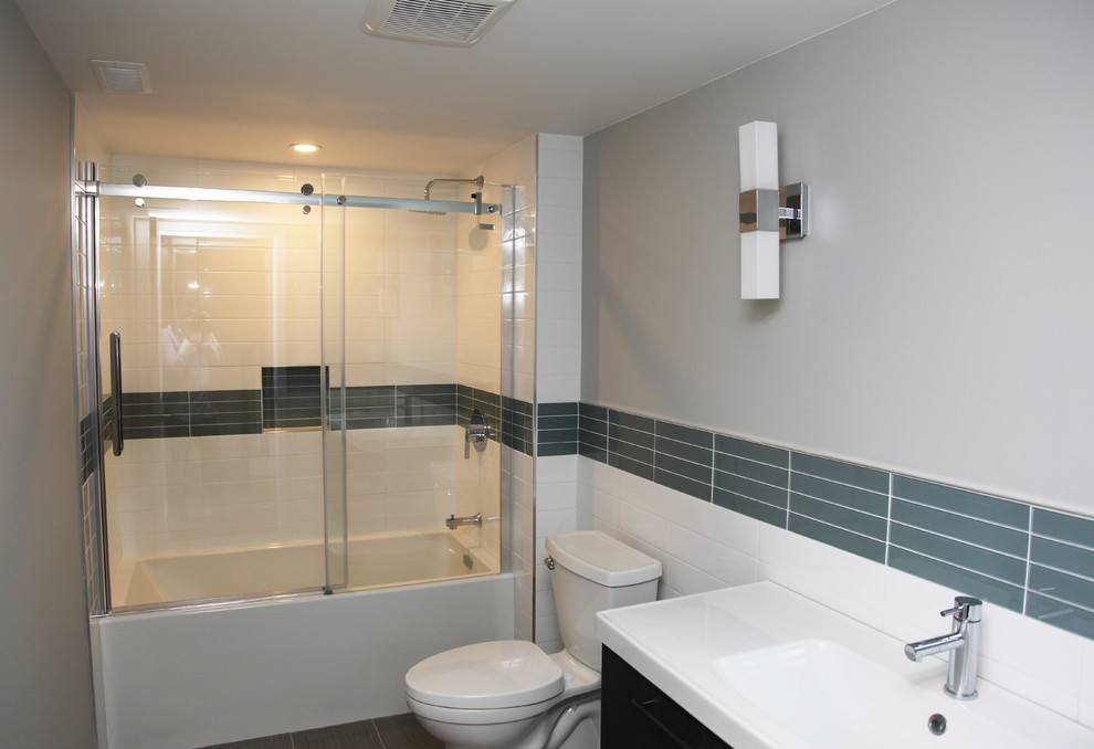 Пример оригинального дизайна: ванная комната среднего размера в стиле модернизм с плоскими фасадами, бежевыми фасадами, ванной в нише, душем над ванной, раздельным унитазом, синей плиткой, белой плиткой, плиткой кабанчик, серыми стенами, душевой кабиной, монолитной раковиной, столешницей из искусственного камня и полом из керамической плитки