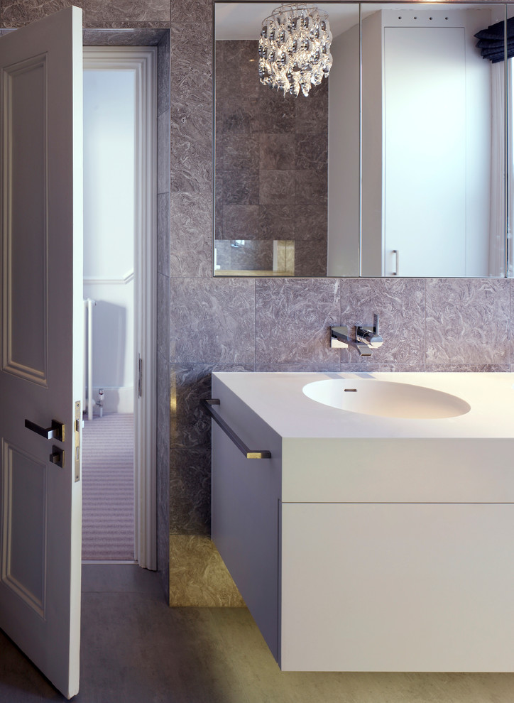 Photo of a large contemporary family bathroom in London with flat-panel cabinets, white cabinets, a built-in bath, a built-in shower, a wall mounted toilet, grey tiles, porcelain tiles, grey walls, porcelain flooring, an integrated sink and engineered stone worktops.