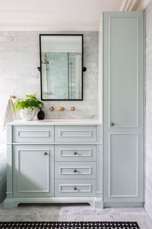Light Green Bathroom Vanity with Marble Backsplash and Brass Knobs