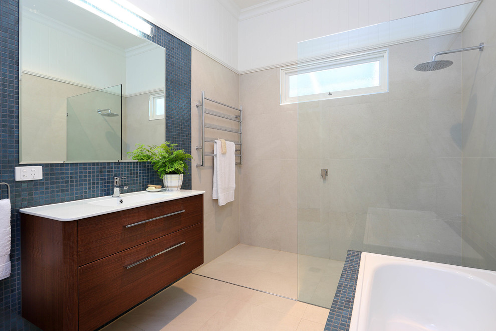 This is an example of a medium sized modern bathroom in Brisbane with an integrated sink, flat-panel cabinets, dark wood cabinets, solid surface worktops, a built-in bath, a walk-in shower, a one-piece toilet, blue tiles, mosaic tiles, beige walls and porcelain flooring.