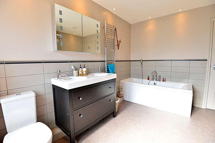 Inspiration for a large contemporary family bathroom in Buckinghamshire with flat-panel cabinets, dark wood cabinets, a built-in bath, a corner shower, a two-piece toilet, grey tiles, porcelain tiles, grey walls, lino flooring and a built-in sink.