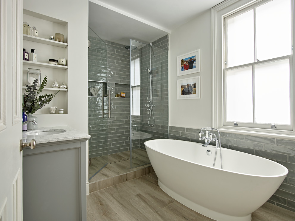Пример оригинального дизайна: ванная комната в морском стиле с серыми фасадами, отдельно стоящей ванной, серой плиткой, белыми стенами, врезной раковиной, душем с распашными дверями, душем в нише, душевой кабиной, бежевым полом и серой столешницей