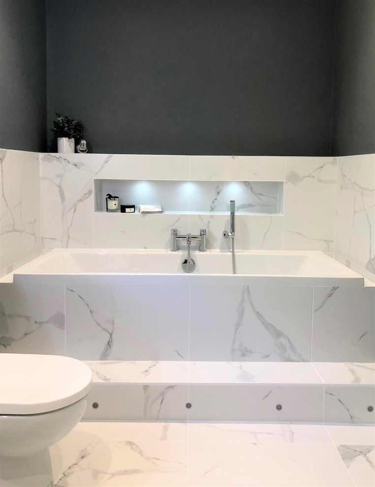 Cette image montre une salle de bain minimaliste de taille moyenne pour enfant avec une baignoire posée, WC séparés, des carreaux de porcelaine, un sol en carrelage de porcelaine et un lavabo suspendu.