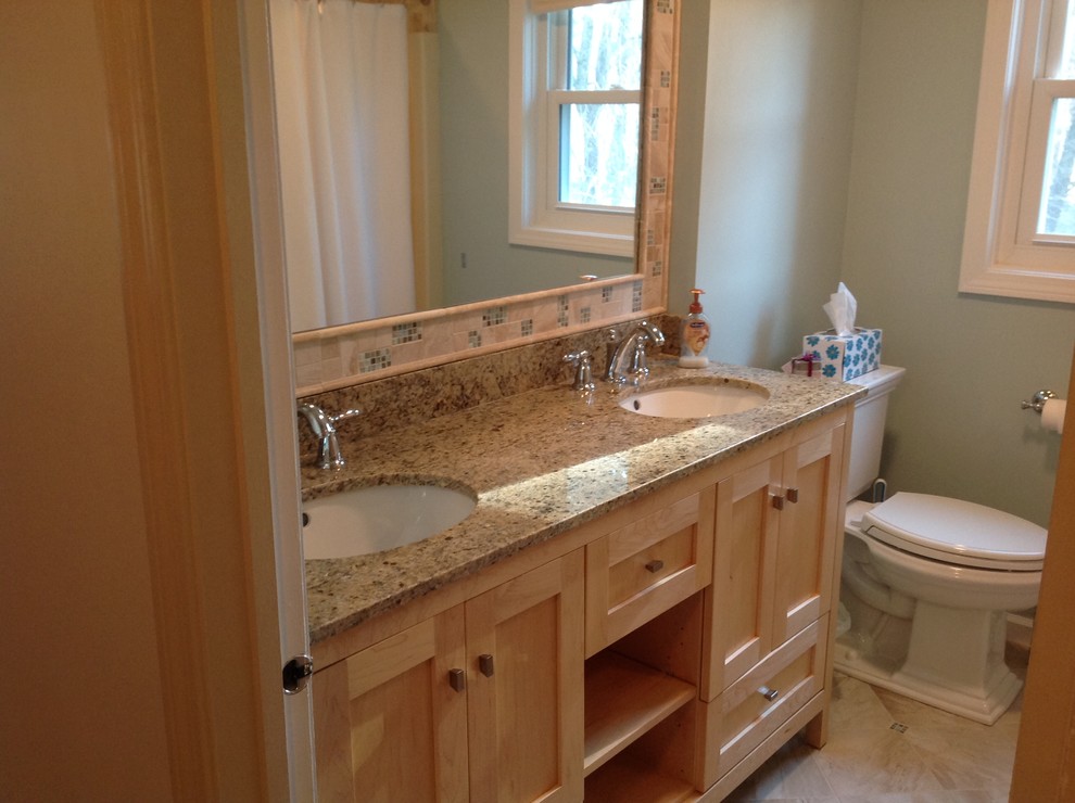 Cette photo montre une salle d'eau chic en bois clair de taille moyenne avec un placard à porte shaker, une baignoire en alcôve, un combiné douche/baignoire, WC à poser, un carrelage beige, des carreaux de porcelaine, un mur bleu, un sol en carrelage de porcelaine, un lavabo encastré, un plan de toilette en granite, un sol beige et une cabine de douche avec un rideau.