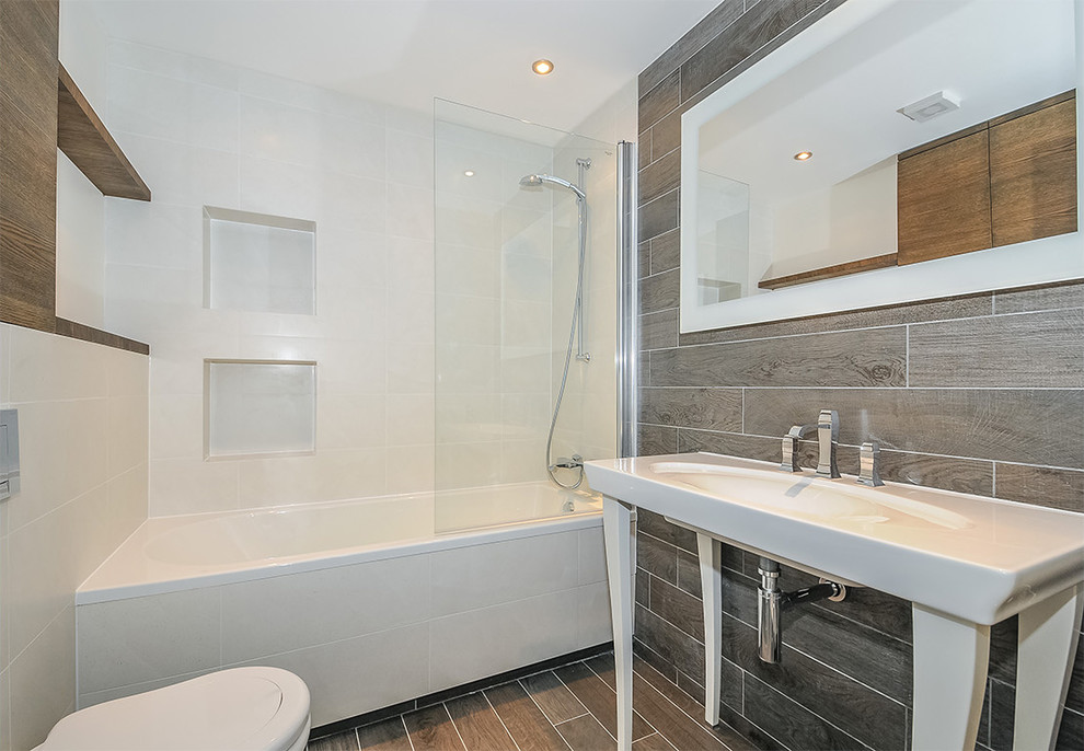 This is an example of a small scandi shower room bathroom in London with flat-panel cabinets, medium wood cabinets, an alcove bath, a shower/bath combination, a wall mounted toilet, brown tiles, a trough sink, porcelain tiles, multi-coloured walls, porcelain flooring, brown floors and an open shower.