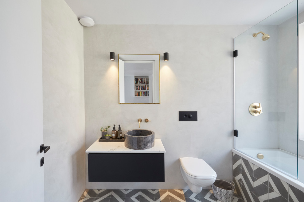 Modernes Badezimmer mit flächenbündigen Schrankfronten, schwarzen Schränken, grauer Wandfarbe, Aufsatzwaschbecken, buntem Boden und weißer Waschtischplatte in London