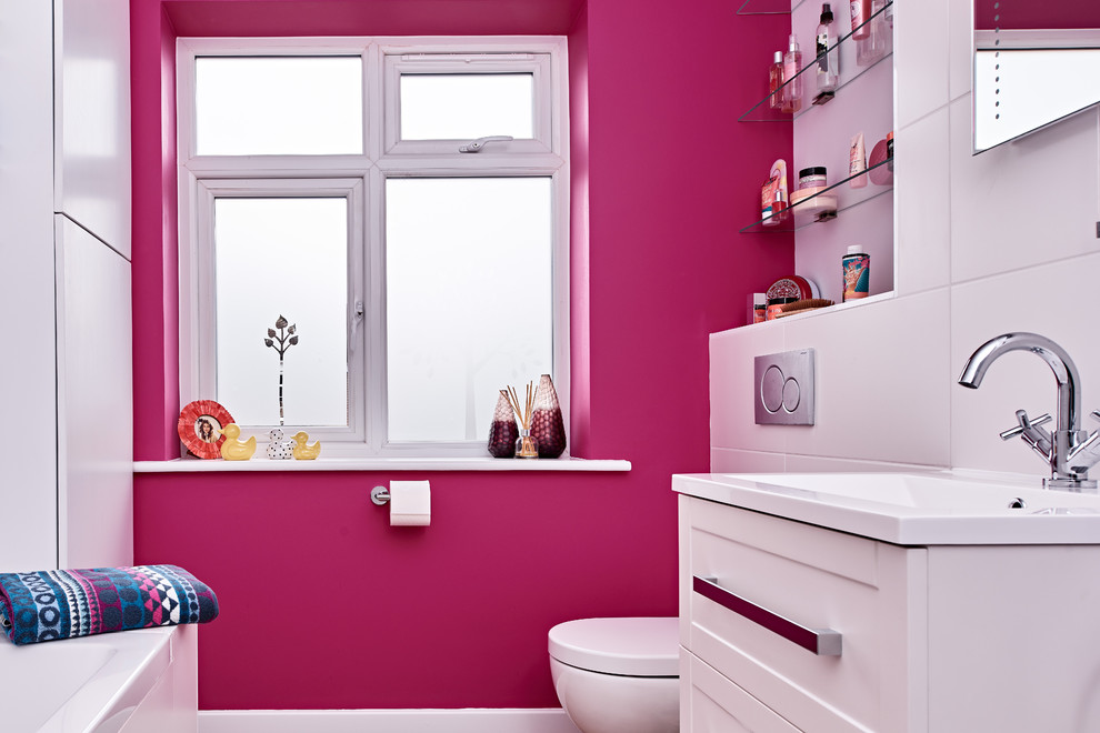 Foto på ett mellanstort funkis badrum för barn, med skåp i shakerstil, vita skåp, ett platsbyggt badkar, en toalettstol med hel cisternkåpa, vit kakel, keramikplattor, rosa väggar och ett väggmonterat handfat