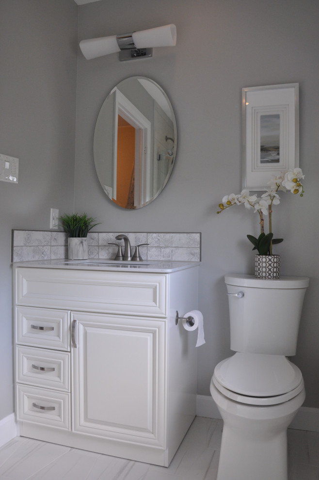 Photo of a medium sized contemporary ensuite bathroom in Ottawa with beaded cabinets, white cabinets, an alcove bath, a shower/bath combination, a two-piece toilet, grey walls, ceramic flooring, a submerged sink, engineered stone worktops, grey floors, a sliding door, grey worktops, a wall niche, a single sink and a freestanding vanity unit.
