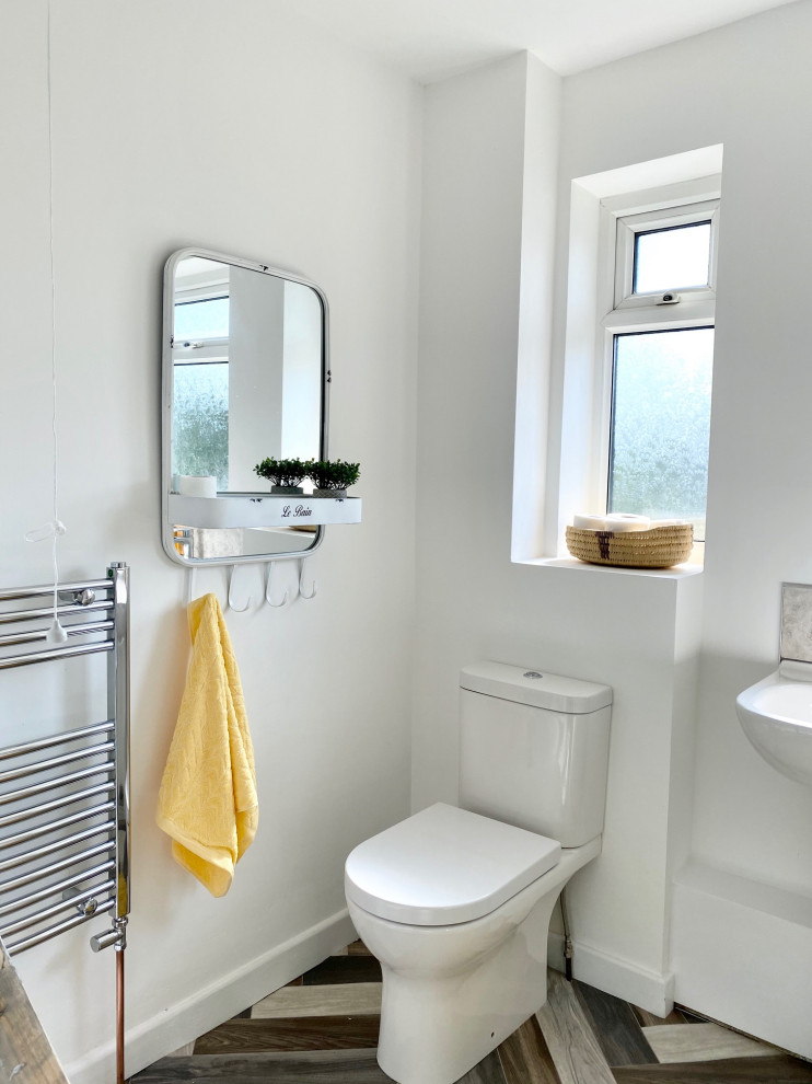 This is an example of a small rural family bathroom in Gloucestershire with a built-in bath, a one-piece toilet, beige tiles, ceramic tiles, white walls, lino flooring, multi-coloured floors, a single sink and a freestanding vanity unit.