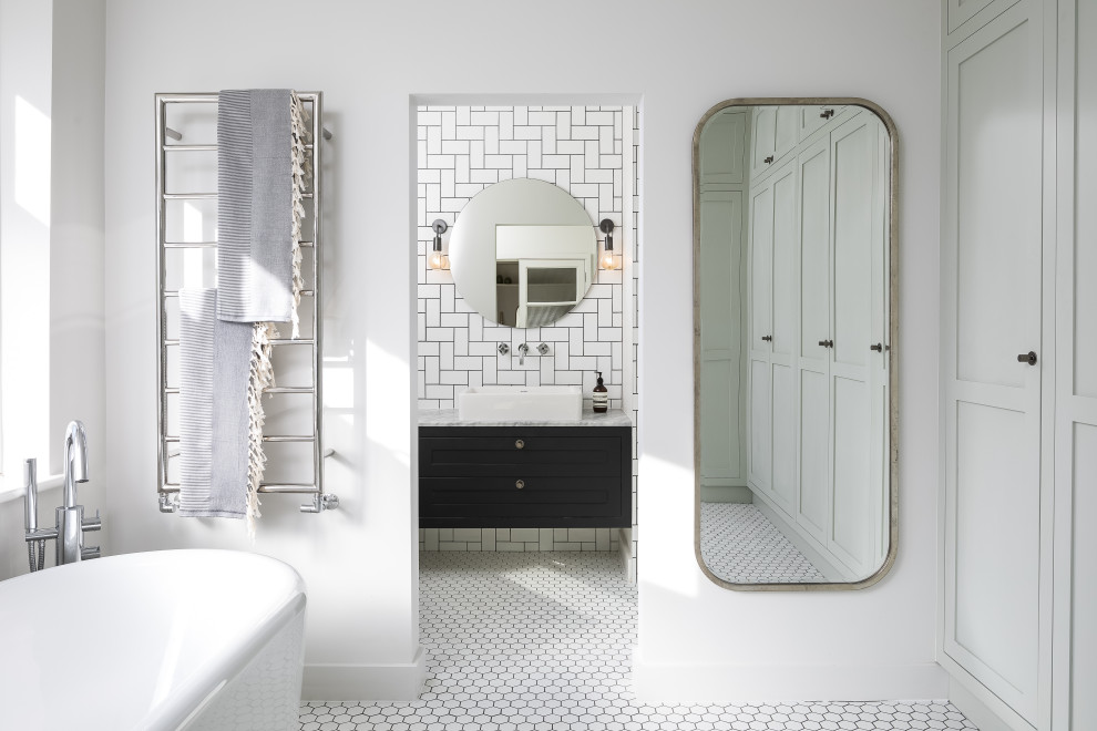 Example of a transitional white tile and subway tile mosaic tile floor and white floor freestanding bathtub design in London with shaker cabinets, black cabinets, white walls, a vessel sink and white countertops