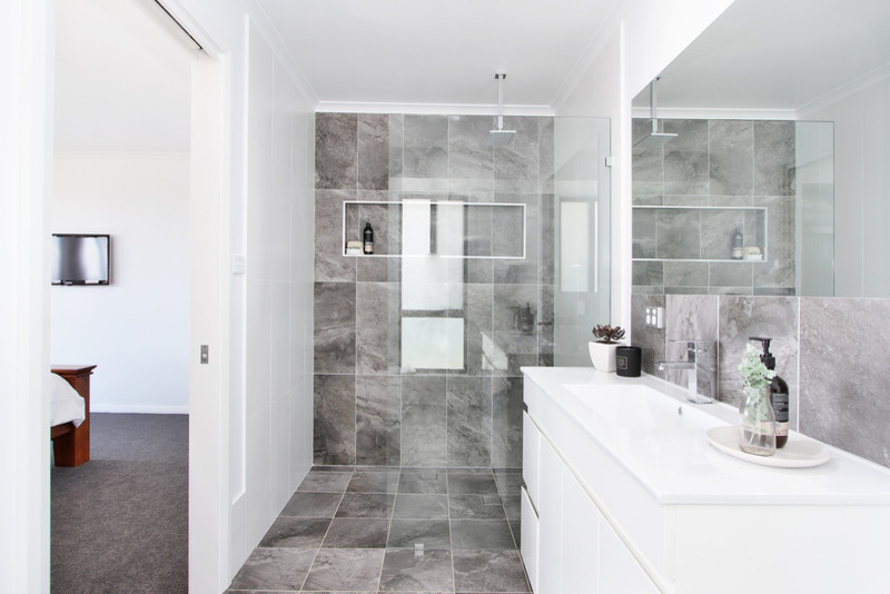 Idée de décoration pour une salle de bain principale minimaliste de taille moyenne avec un espace douche bain, un carrelage gris, un sol gris, un plan de toilette blanc, un placard à porte plane, des portes de placard blanches, des carreaux de céramique, un mur blanc et un sol en carrelage de céramique.