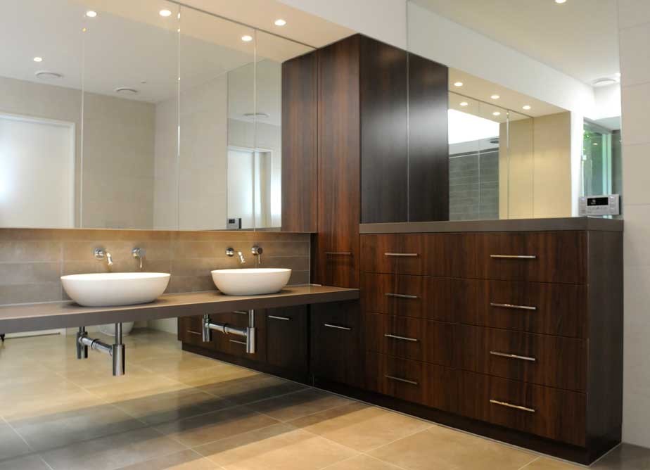 Large contemporary ensuite bathroom in Melbourne with a vessel sink, flat-panel cabinets, medium wood cabinets, engineered stone worktops, a freestanding bath, a walk-in shower, a one-piece toilet, beige tiles, porcelain tiles, beige walls and porcelain flooring.