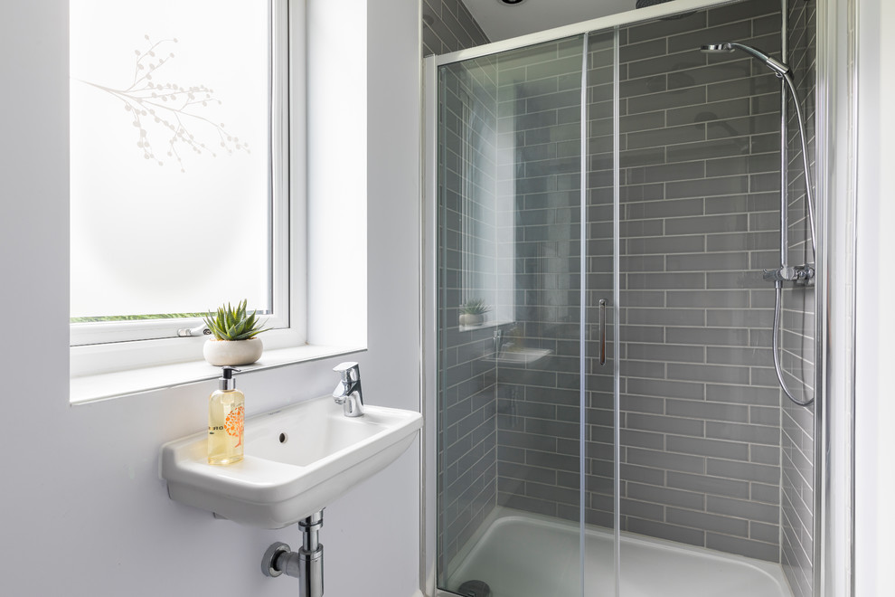 Photo of a small traditional shower room bathroom in Oxfordshire with a wall mounted toilet, grey tiles, ceramic tiles, white walls, ceramic flooring, a wall-mounted sink, grey floors, a sliding door and a walk-in shower.