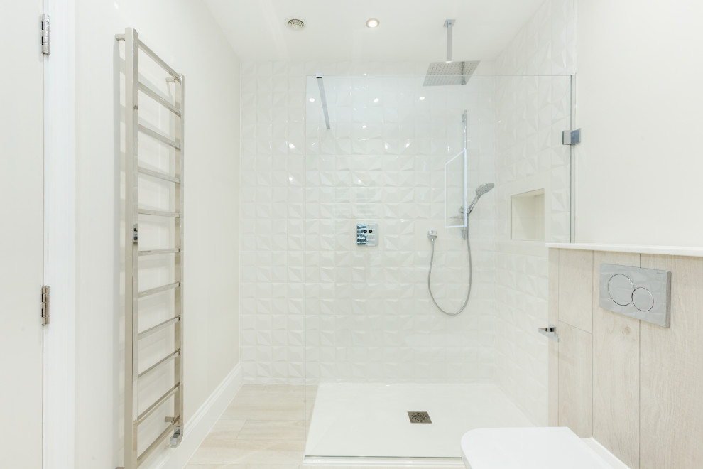 Foto på ett mellanstort funkis badrum, med en hörndusch, en toalettstol med hel cisternkåpa, vit kakel, vita väggar och med dusch som är öppen
