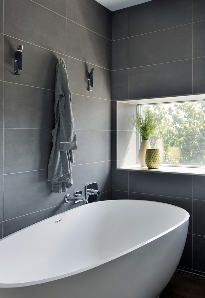 Idée de décoration pour une salle de bain principale design avec une baignoire indépendante, un carrelage gris et un mur gris.
