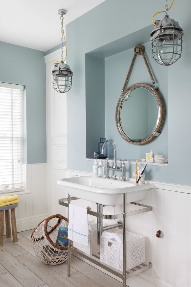 Small beach style master light wood floor bathroom photo in London with blue walls and a console sink
