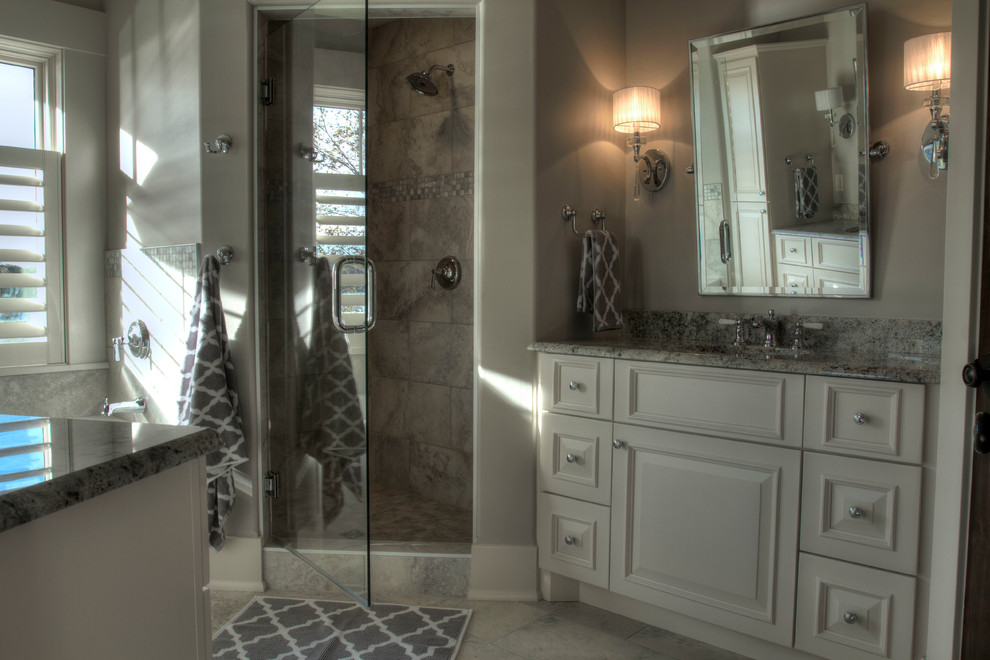 Photo of an expansive traditional bathroom in Minneapolis with raised-panel cabinets, white cabinets, a built-in bath, a corner shower, a one-piece toilet, grey tiles, porcelain tiles, grey walls, ceramic flooring, a built-in sink and granite worktops.