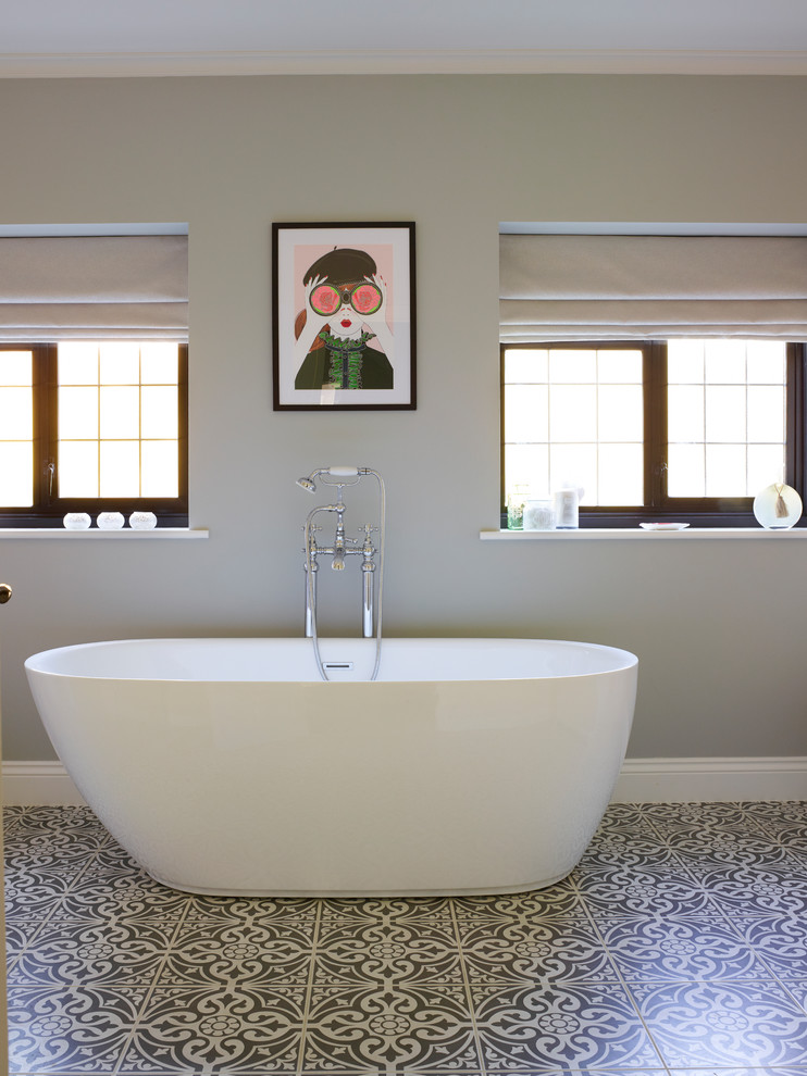 Bild på ett funkis badrum, med ett fristående badkar, grå väggar och grått golv