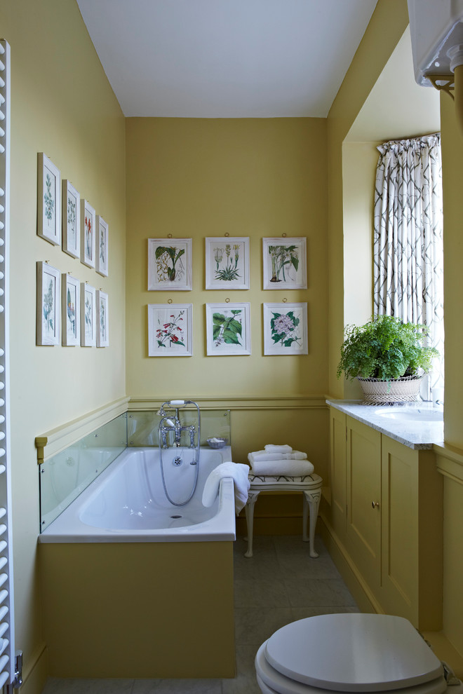 Idées déco pour une salle de bain grise et jaune classique avec un lavabo encastré, un placard à porte shaker, des portes de placard jaunes, une baignoire posée et un mur jaune.